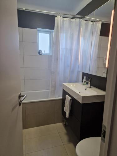 La salle de bains est pourvue d'un lavabo, d'une baignoire et de toilettes. dans l'établissement Sól - S12 guesthouse, à Keflavík