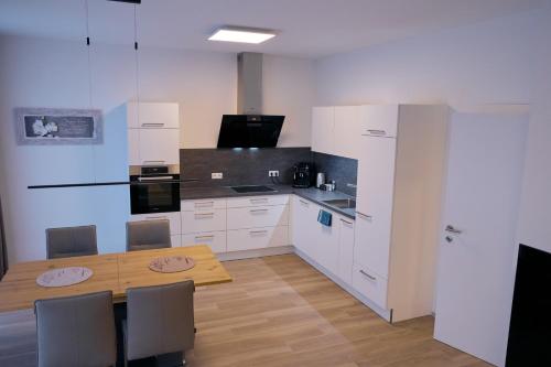 a kitchen with white cabinets and a wooden table at Deluxe Apartment Leibnitz in Leibnitz
