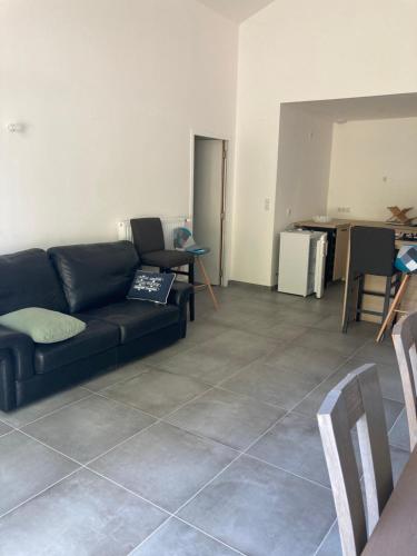 a living room with a black couch and a tile floor at Le Cysphée chez Christelle in Sallertaine