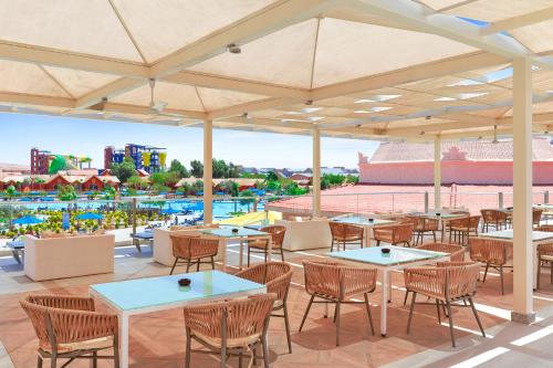 an outdoor patio with tables and chairs and a pool at Pickalbatros Jungle Aqua Park - Neverland Hurghada in Hurghada