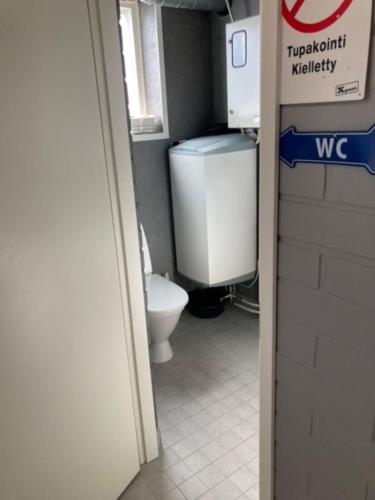 a bathroom with a toilet and a sign on the door at Alanko Lodge in Tornio