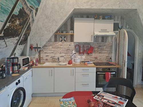 a kitchen with white cabinets and a brick wall at LA TOURELLE in Morlaix