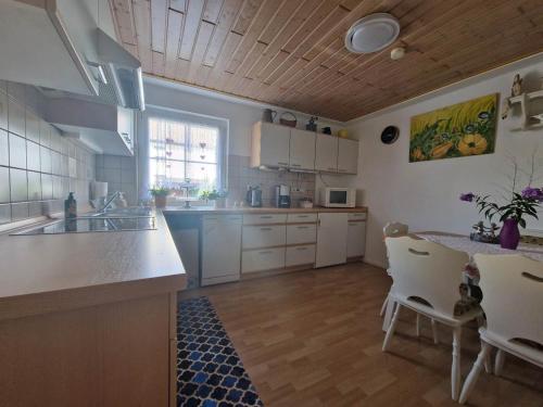 a large kitchen with white cabinets and a table and chairs at FeWo Schellenbergstraße in Kißlegg