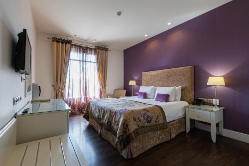 a hotel room with a bed and a purple wall at Nymfasia Resort in Vytina