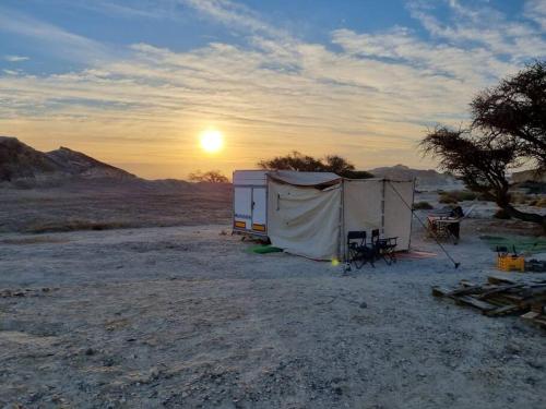un grupo de tiendas en el desierto con la puesta de sol en ג'וני- חוויה בקארוון מדברי, en Sappir
