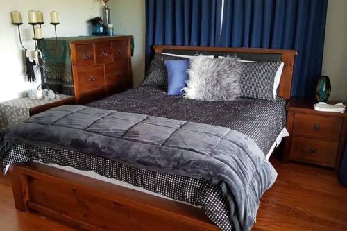 Riverview Place في تاري: غرفة نوم بسرير كبير مع ستائر زرقاء