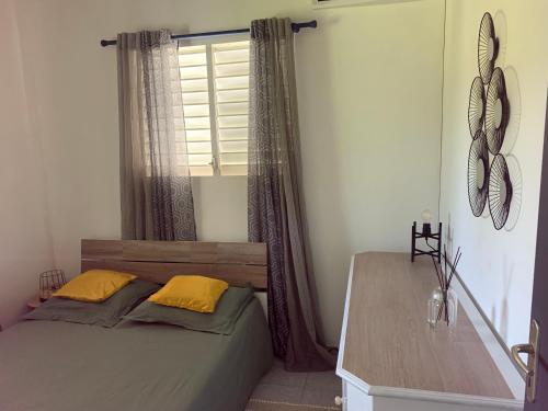 sypialnia z łóżkiem z żółtymi poduszkami i oknem w obiekcie La Verdure w mieście Petit-Bourg
