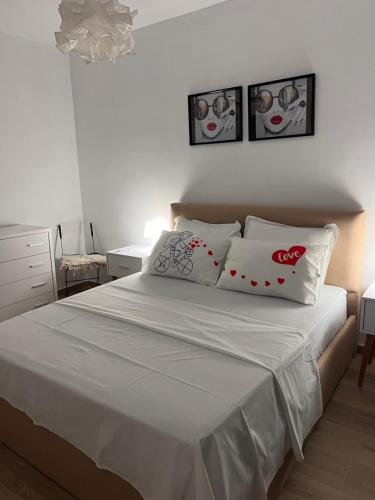 een slaapkamer met een bed met witte lakens en kussens bij Sunset Resort in Vlorë