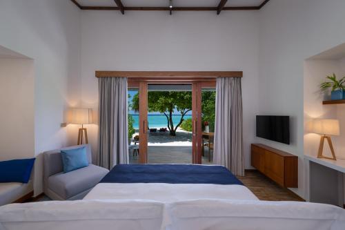 a bedroom with a bed and a sliding glass door at Ifuru Island Resort Maldives - 24-Hours Premium All-inclusive with Free Domestic Transfer in Raa Atoll