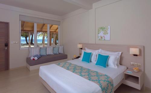 a bedroom with a bed with blue and white pillows at Malahini Kuda Bandos Resort in North Male Atoll