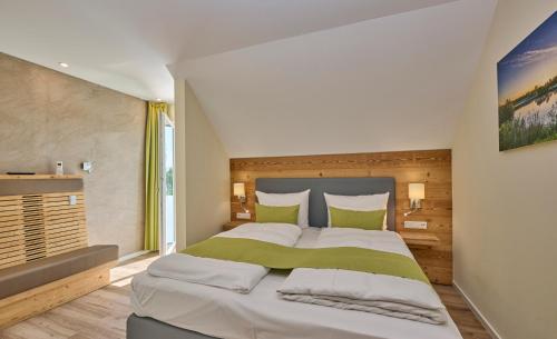 Bachhof Resort Apartments في Kirchroth: غرفة نوم بسرير كبير ومخدات خضراء وبيضاء