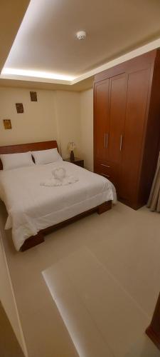 a bedroom with a large bed and a wooden cabinet at City Garden Pattaya - 2br Suite, 76sqm in Pattaya Central