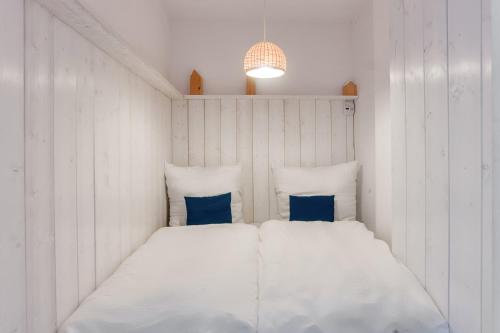 a bed in a room with white walls and blue pillows at Hein Krabbe Heiligenhafen in Heiligenhafen