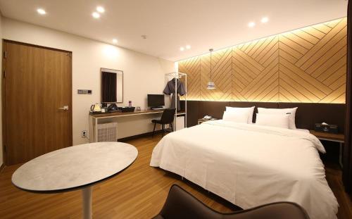a hotel room with a bed and a table and a desk at Brown Dot Hotel Sinan in Gwangju