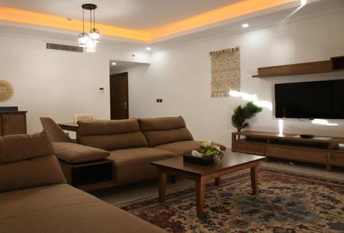YM Resort في ينبع: غرفة معيشة مع أريكة وتلفزيون بشاشة مسطحة
