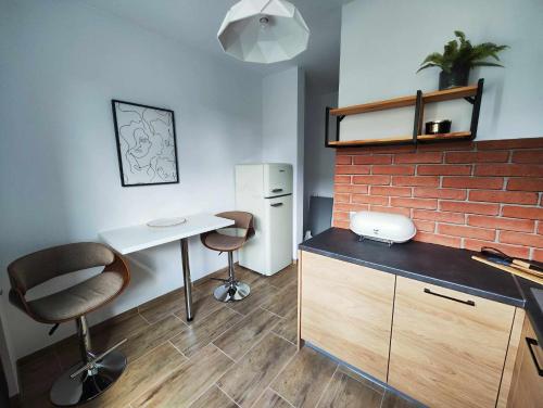 cocina con escritorio, sillas y pared de ladrillo en Centrum Miasta, en Stargard