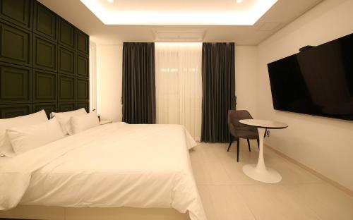 a bedroom with a bed and a table and a tv at Brown Dot Hotel Sinan in Gwangju