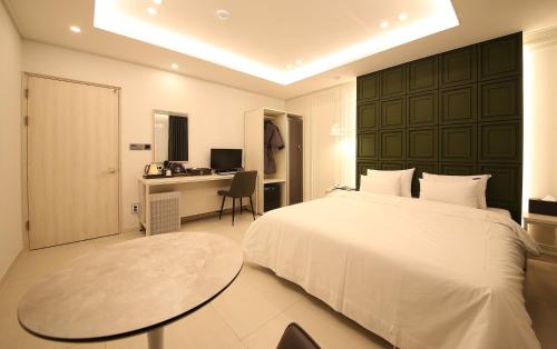 a bedroom with a bed and a desk and a table at Brown Dot Hotel Sinan in Gwangju