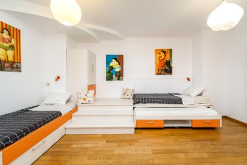 two beds in a room with paintings on the walls at Apartment Botero in Belgrade