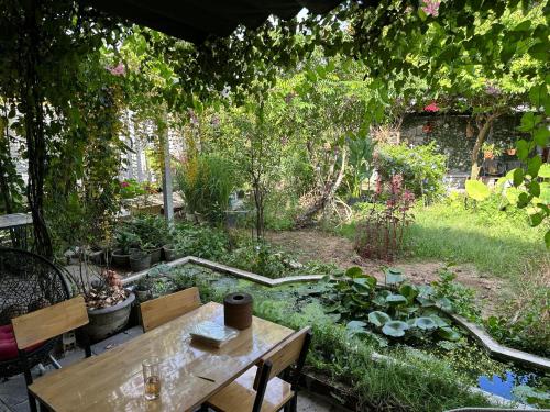 einen Garten mit einem Holztisch und einem Teich in der Unterkunft Vom Vom Garden House in Đà Nẵng