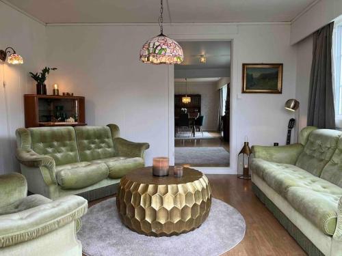 a living room with green couches and a coffee table at Nakkentunet - familievennlig hus på gårdstun. in Ørskog