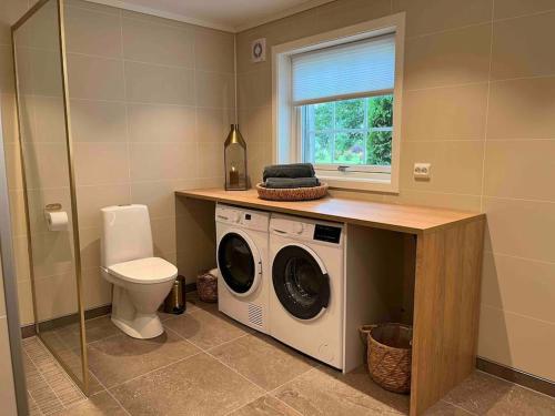 a bathroom with a washing machine and a toilet at Nakkentunet - familievennlig hus på gårdstun. in Ørskog