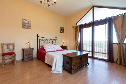 1 dormitorio con 1 cama, 1 silla y 1 ventana en Los Rosales de Venturada, en Venturada