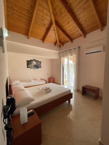a bedroom with a large bed and a wooden ceiling at Belvedere Hotel & Suites in Himare