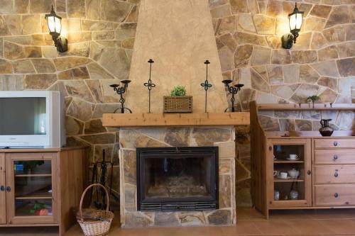ein Wohnzimmer mit Kamin und Fernseher in der Unterkunft Los Rosales de Venturada in Venturada