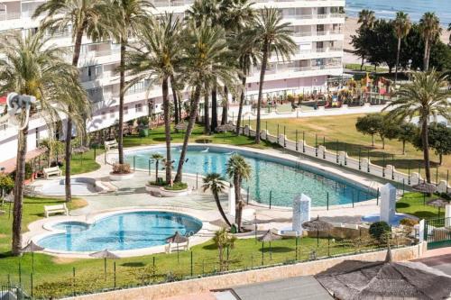 Blick auf einen Pool mit Palmen und ein Gebäude in der Unterkunft apartamento al mar cullera florazar in Cullera