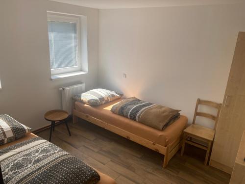 a room with two beds and a chair and a window at Penzion Norden in Mariánské Radčice