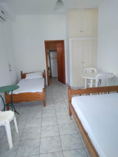 a room with two beds and a table and chairs at Floisvos Apartments in Selianitika