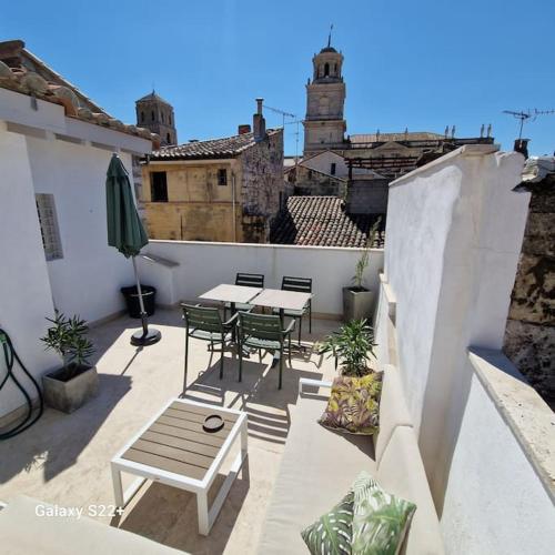 un patio con mesas y sillas en el balcón en The Rooftop Arles - Terrasse panoramique, en Arles