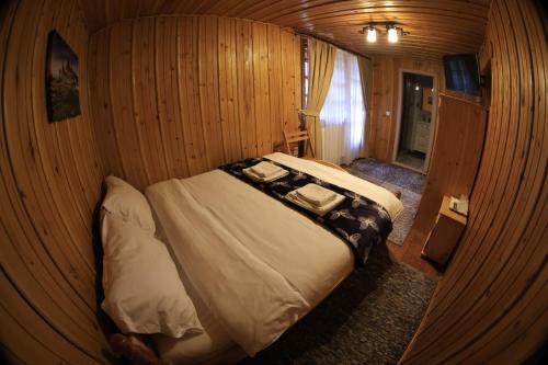 una piccola camera con un letto su una parete in legno di Cabana Gura Voronețului a Gura Humorului