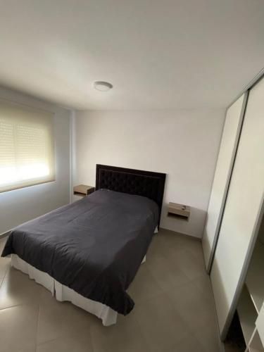 1 dormitorio con 1 cama en una habitación blanca en Departamento D en Bahía Blanca