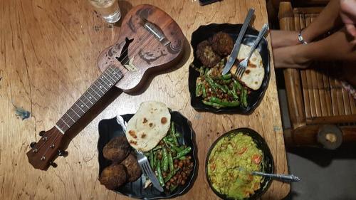 uma mesa de madeira com pratos de comida e uma guitarra em Georgia's Neverland Hostel em Malapascua