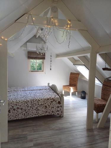um quarto com uma cama e 2 cadeiras em B&B Het mooie uitzicht em Reuver