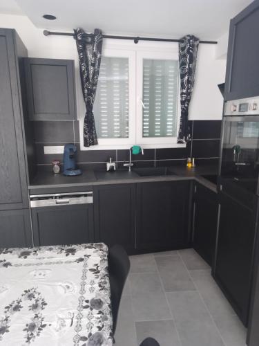 eine Küche mit schwarzen Schränken, einem Waschbecken und einem Fenster in der Unterkunft appartement T2 neuf et design in Pérignat-lès-Sarliève
