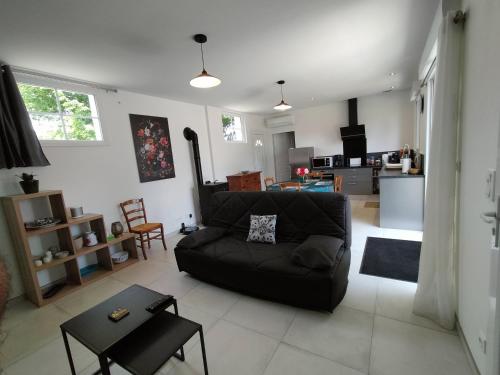 sala de estar con sofá negro y mesa en Maison pour 4/ 6 personnes les hirondelles, en Saint-Vivien-de-Monségur