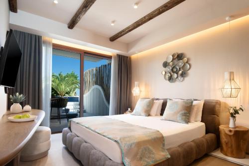 a bedroom with a large bed and a balcony at Alexandra Golden Boutique Hotel-Adults Only in Chrysi Ammoudia