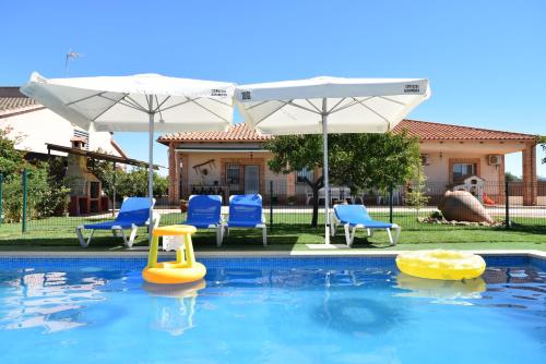 einen Pool mit zwei Sonnenschirmen und Stühlen sowie einem Poolspielzeug in der Unterkunft La Casona del Bullaque in El Robledo