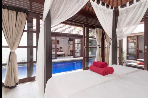 a red elephant laying on a bed in front of a pool at Villa Kubu Pratiwi - Villa 2 in Canggu