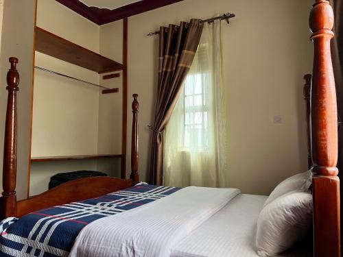 a bedroom with a canopy bed and a window at Pearl Sanctuary 02_Kisoro Homestay in Kisoro