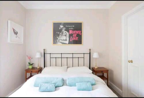 倫敦的住宿－Boho Chic in Chelsea，卧室配有带蓝色枕头的大型白色床