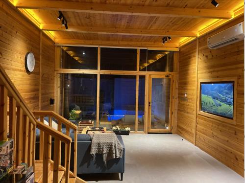 una sala de estar con paredes de madera y una gran ventana. en أكواخ البحيرات, en Khalij Salman