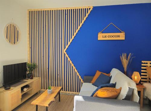 un salon avec un canapé et un mur bleu dans l'établissement Le Cocon, Studio à 5 min de la gare de Grenoble, à Grenoble