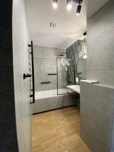 a bathroom with a shower and a tub and a sink at Hotel Kresowianka in Konin