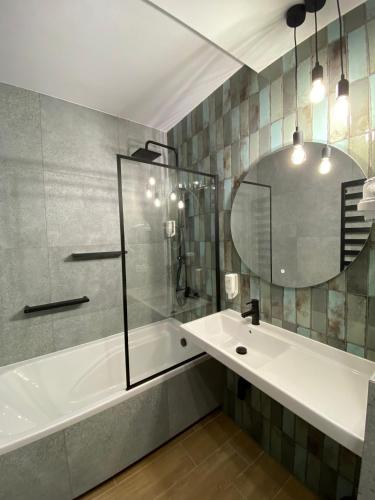 a bathroom with a tub and a sink and a mirror at Hotel Kresowianka in Konin