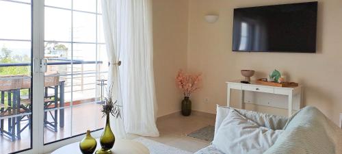 Una sala de estar con un sofá y un televisor en una pared. en Nama Beach House, en rkadiko Chorio