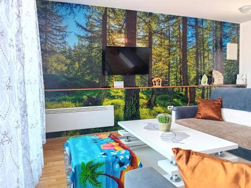 a living room with a large window with a forest mural at Apartman "AROMA 1"Bjelasnica in Bjelašnica